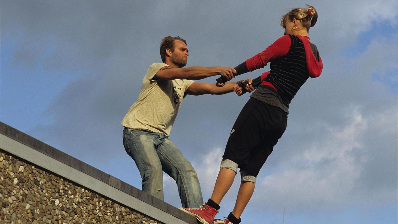 Mann hält Frau auf einer Dachkante fest 