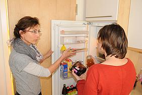 Nach einem Ordnungssystem den Kühlschrank einräumen: Diese ist eine von zahlreichen Initiativen, die Hauswirtschafterin Maria Breitenhuber (links) mit Andrea G. im Training „Fit für den Haushalt“ unternommen hat. pde-Foto: Caritas/Esser