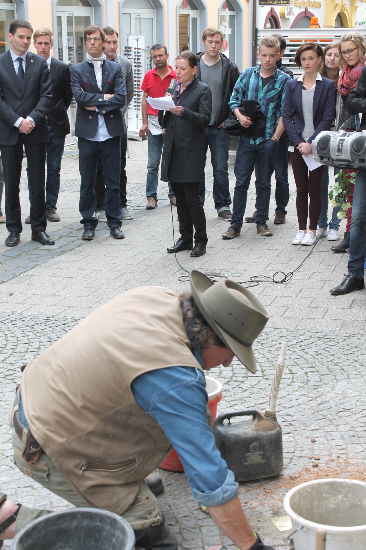 Der Künstler Gunter Demnig verlegt einen Stolperstein in der Marktgasse, Dr. Claudia Grund spricht ein Grußwort. Foto: Heberling