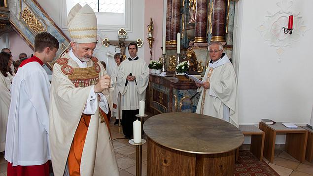 Bischof Hanke besprengt den neuen Altar mit Weihwasser. 