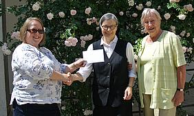 Dr. Christine Zimmermann (links im Bild), überreicht zusammen mit der Schatzmeisterin Ingrid Eder (rechts) den Scheck an Sr. Antonia Stegmiller.