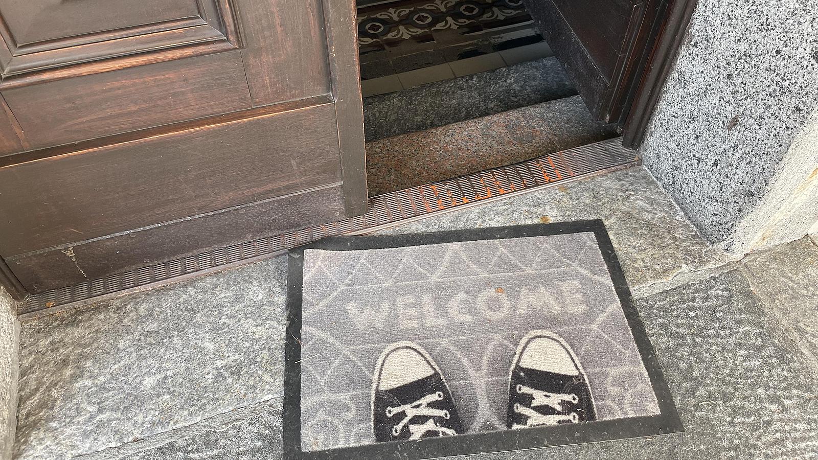 Fußmatte mit Schriftzug Welcome for einer Tür.