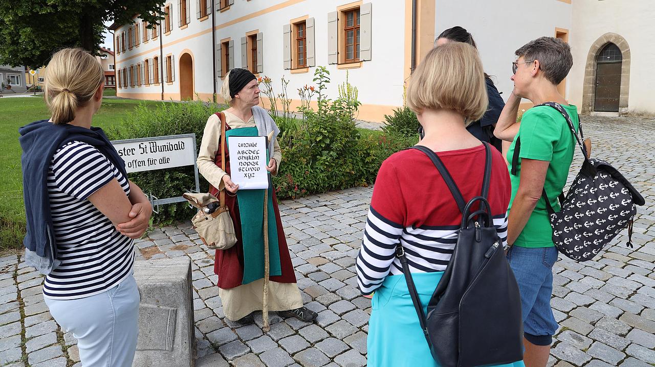 Frauenreferentin Martha Gottschalk, alias „Walburga“, spricht mit Pilgern vor dem Münster Heidenheim. 