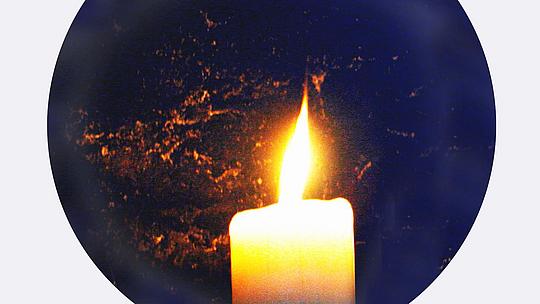 Eine brennende Kerze vor einer Weltkugel