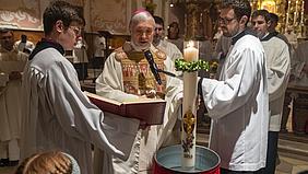 In der Osternacht senkt Bischof Gregor Maria Hanke die Osterkerze in das Taufwasser