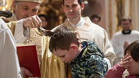 Bischof Gregor Maria Hanke tauft einen Jungen
