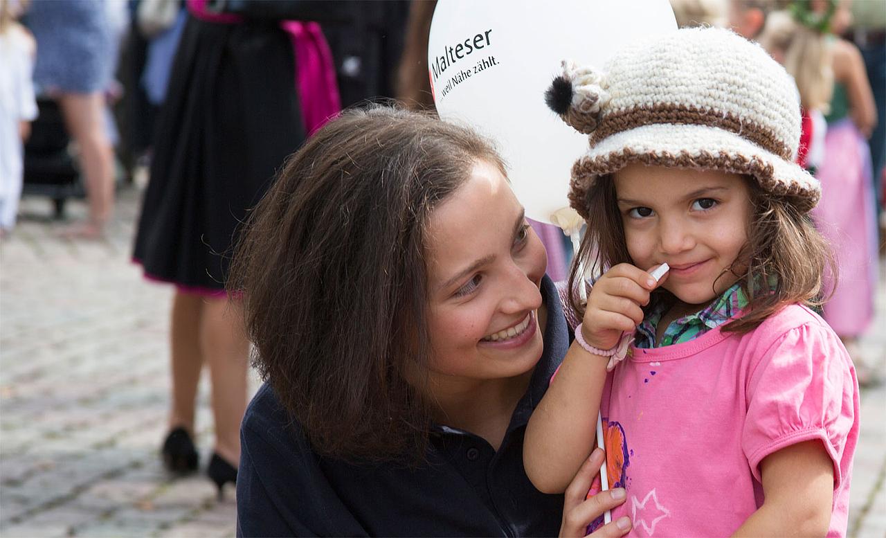 Malteser-Mitarbeiterin mit Flüchtlingskind beim Volkfestumzug in Eichstätt. Foto: Anika-Taiber Groh