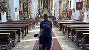 Malteser-Mitarbeiter mit Rollstuhlfahrerin in der Wallfahrtskirche Bergen