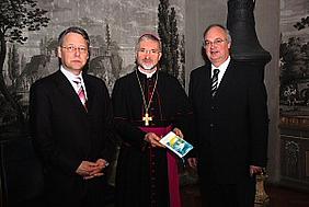 Professor Bernhard Sill (links) und Domvikar Reinhard Kürzinger (rechts) übergeben das erste Exemplar ihres Gebetbuches „Durchs Leben getragen“ an Bischof Dr. Gregor Maria Hanke OSB.
