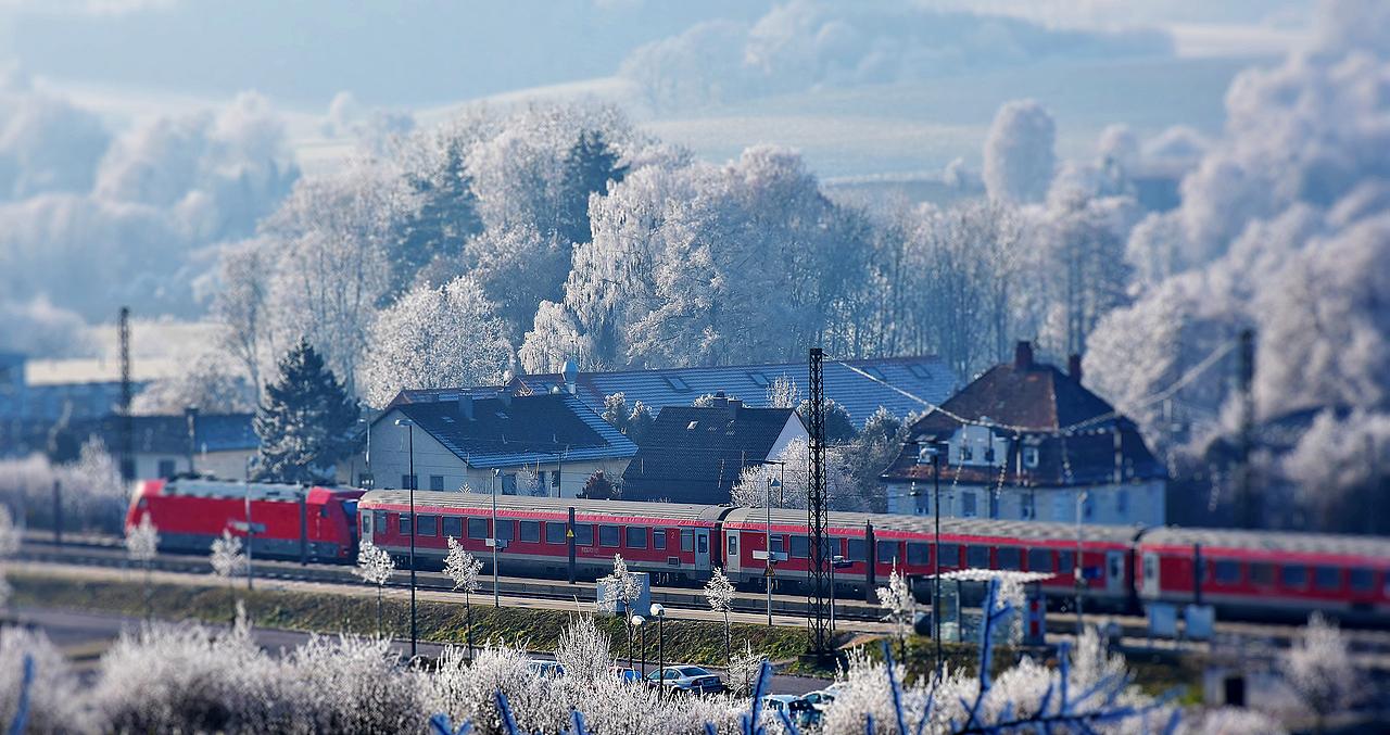 roter Zug fährt durch eine Winterlandschaft