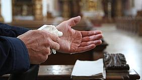 Person desinfiziert sich die Hände in einer Kirche