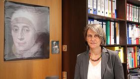 Schulleiterin Ulrike Rhein neben einem Bild von Maria Ward, der Namensgeberin der Fachakademie für Sozialpädagogik der Diözese Eichstätt.