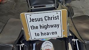 Motorrad mit Schild mit der Aufschrift Jesus Christ the highway to heaven. 