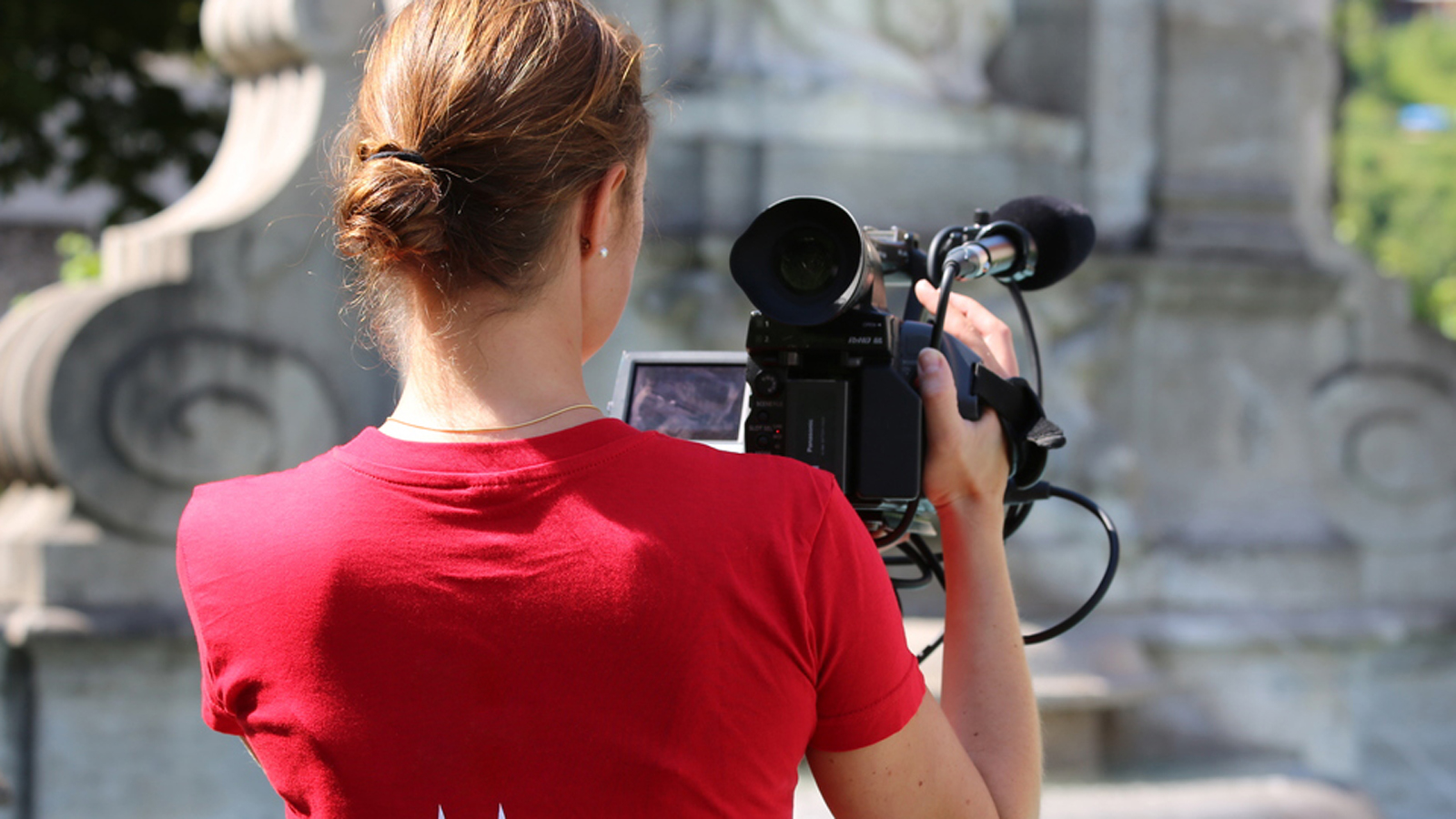 Journalistin von hinten mit einer Videokamera